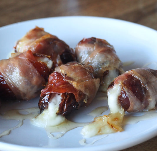 Prosciutto wrapped around dates that have been stuffed with salami and brie cheese